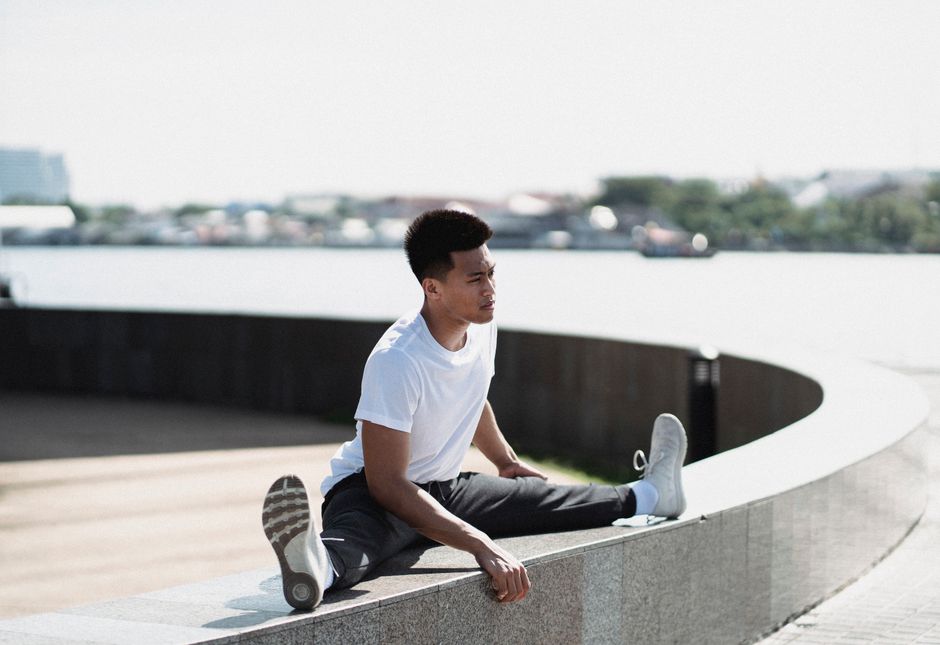 Deportista Asiático Flexible Sentado En La Frontera Y Estirando Las Piernas