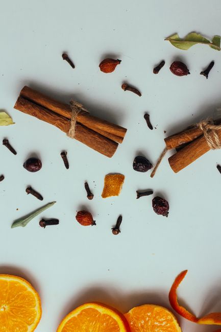 Una disposición plana de ramas de canela, clavos de olor y rodajas de naranja, perfecta para temas culinarios.