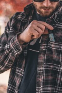 Acercamiento de un hombre poniendo un producto de CBD en el bolsillo de su camisa en un día de otoño.
