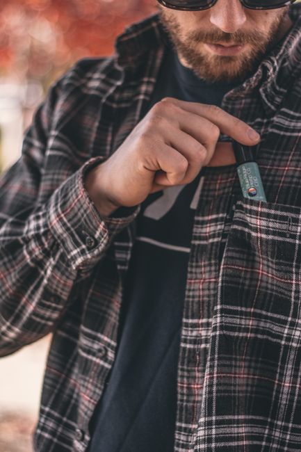 Acercamiento de un hombre poniendo un producto de CBD en el bolsillo de su camisa en un día de otoño.
