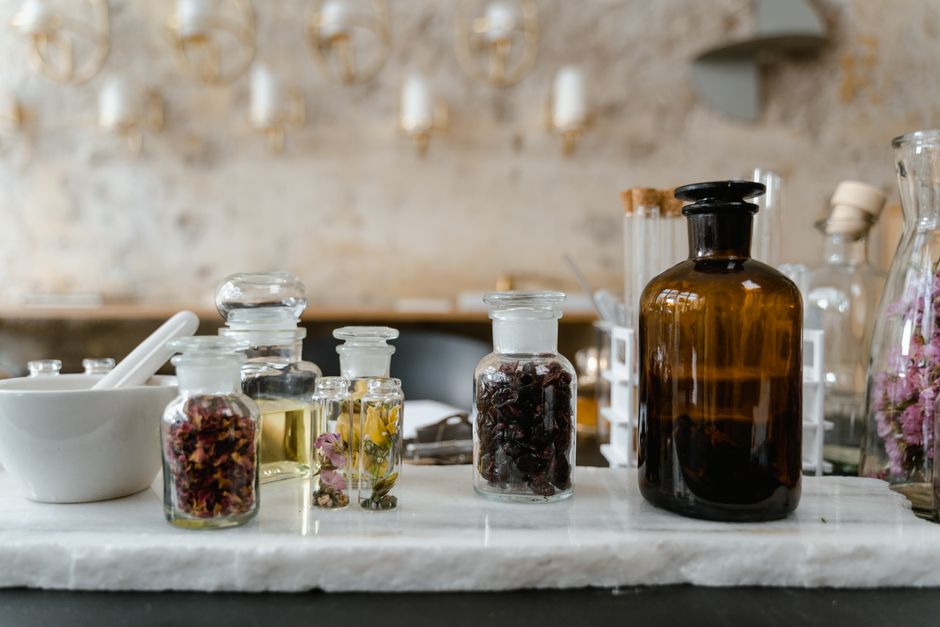 Exhibición estética de aceites esenciales y flores secas en botellas de vidrio para uso en aromaterapia.