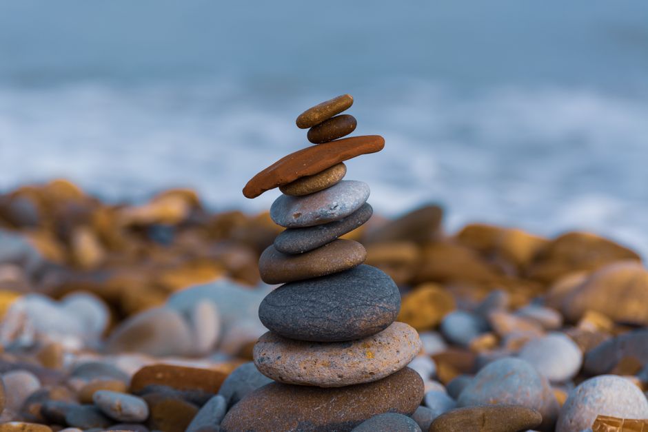 Primer plano de una pila equilibrada de piedras en una playa rocosa, promoviendo serenidad y zen.