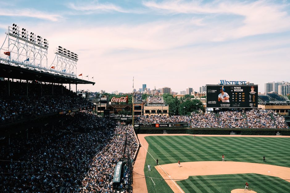 Toma aérea de un abarrotado juego de béisbol en Wrigley Field, mostrando el vibrante paisaje urbano de Chicago.
