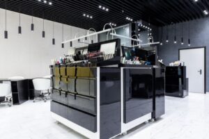 Interior elegante de tienda de maquillaje con gabinetes negros brillantes, sillas y abundante iluminación.