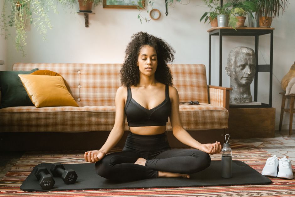 Una mujer meditando en una sala de estar tranquila, encarnando la atención plena pacífica.