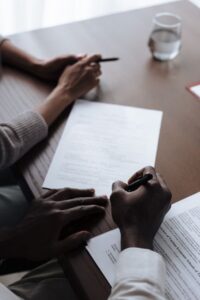 Escena íntima de una pareja firmando documentos importantes de adopción en casa, destacando la diversidad y la paternidad.