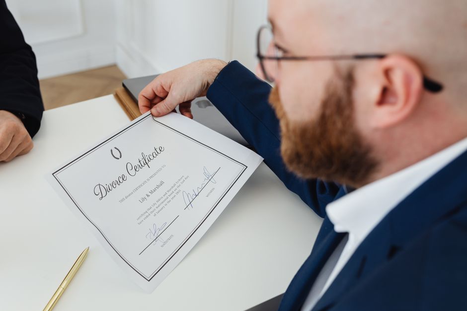 Un hombre sosteniendo un certificado de divorcio en un entorno de oficina formal.