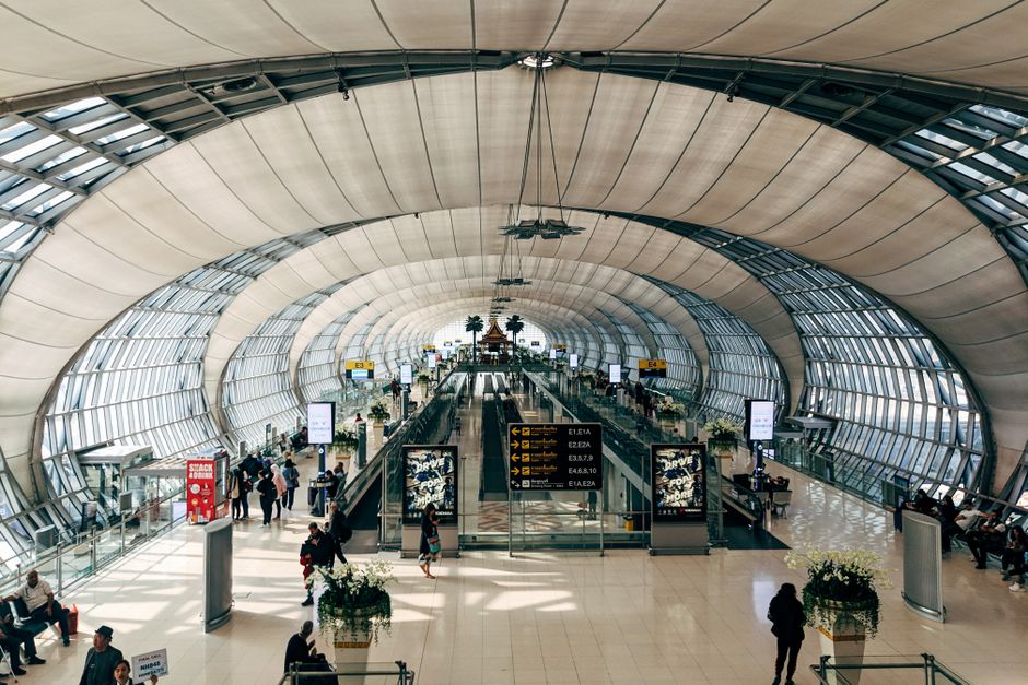 Vista en ángulo alto de los modernos interiores del Aeropuerto Suvarnabhumi, llenos de pasajeros en Bangkok.